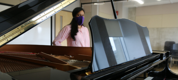 Soprano Adriana Orozco Burbano wearing a face covering behind a piano