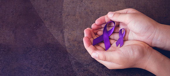Photo of two purple ribbons in a palm of a hand