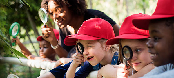 Four children and a teacher looking at plants.