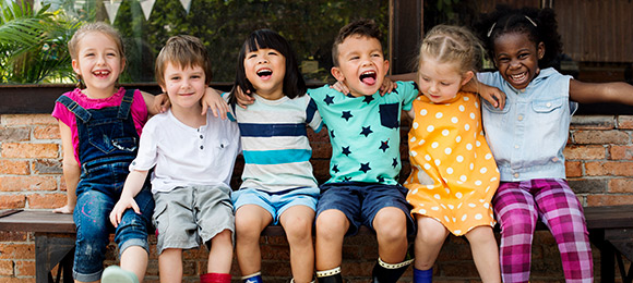 Six children smiling and with their arms around each other.