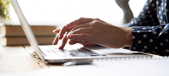 A pair of hands typing on a laptop computer.