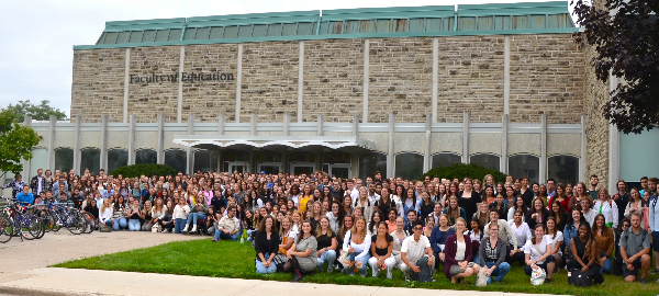 Hundreds of Teacher Candidates pose of a photo on the front lawn of the Faculty of Education Building.