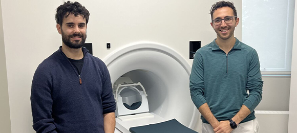Two graduate students standing infront of an MRI machine